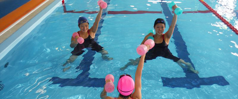 ダンベルを持って水中で運動している女性たち